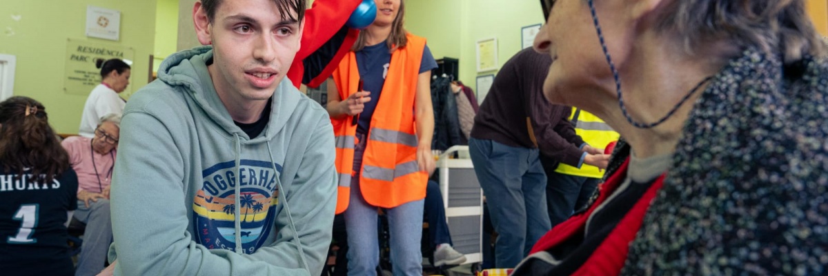 En ung VITA Explorer taler med en ældre beboer på et plejehjem under en intergenerationel aktivitet, faciliteret af deltagere.