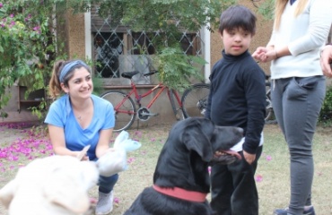 Et barn sammen med en sort hund og en smilende VITA Explorer under en session med hundeterapi arrangeret af VITA.