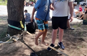 En VITA-deltager hjælper en dreng med at gå på slackline, spændt op under et træ, under en udendørs aktivitet i Córdoba, Argentina.