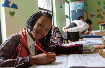 Smilende elev San skriver i sin notesbog under undervisningen på en community-skole i Namibia som del af et VITA-uddannelsesprojekt.