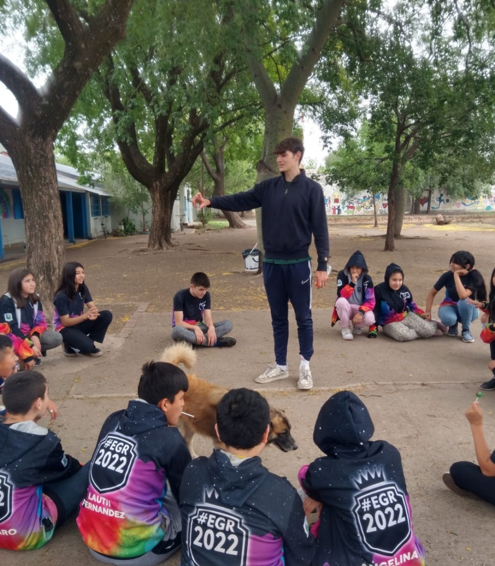 En VITA-deltager leder en udendørs læringsaktivitet med en gruppe børn i Córdoba, Argentina, under grønne træer.